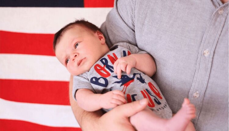 طفل يحمله والده خلفهم علم امريكا -الولادة في أمريكا