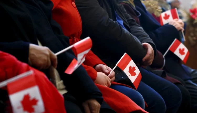 أشخاص يحملون علم كندا - إعادة التوطين في كندا