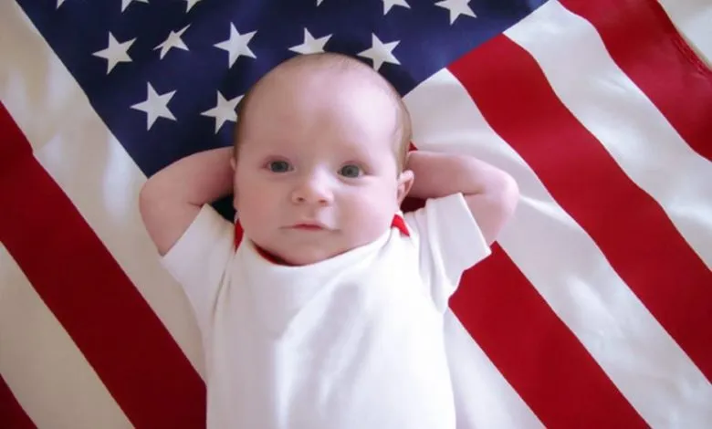 طفل مستلقي فوق العلم الامريكي- الولادة في امريكا 